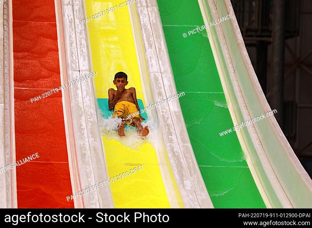 19 July 2022, Iraq, Baghdad: A Iraqi boy goes down a water slide at an Aqua Park amid an ongoing heatwave in Iraq. Iraq experiences a heatwave with temperatures...