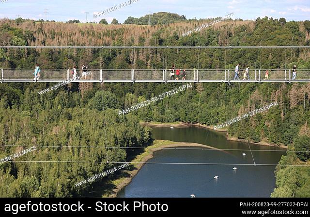 23 August 2020, Saxony-Anhalt, Blankenburg: Visitors walk on the suspension bridge Titan RT near the Rappbode dam. Bright sunshine again attracted many guests...