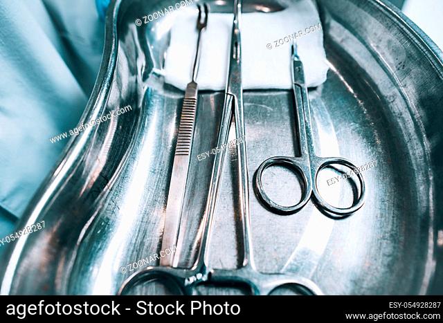 Several surgical instruments lie on a tray, close perspective