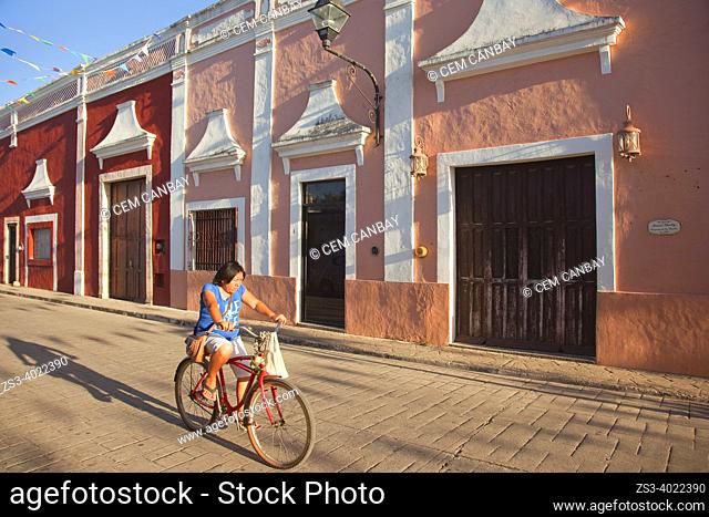 Cyclist in front of the colorful colonial buildings at the historic center, Valladolid, Yucatan Province, Mexico, Central America