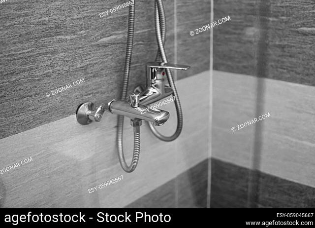 Modern designer tap and shower in bathroom. Closeup of chrome shower, faucet, in the bathroom covered decorative ceramic. Mixer cold hot water