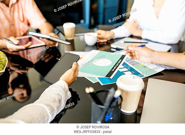 Close-up of coworkers working together on table
