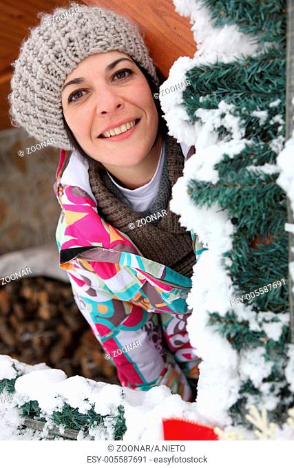 Woman behind snowy tree