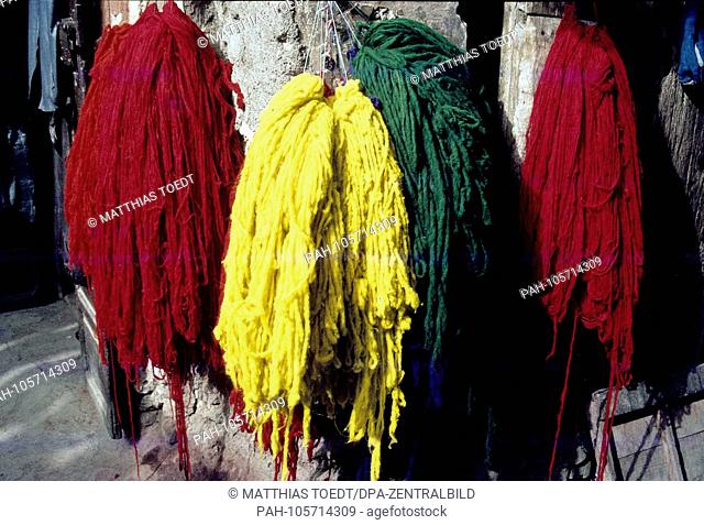 Freshly dyed woolen bulbs are offered for sale after drying in the old town of Marrakech, analogue undated image from March 1985