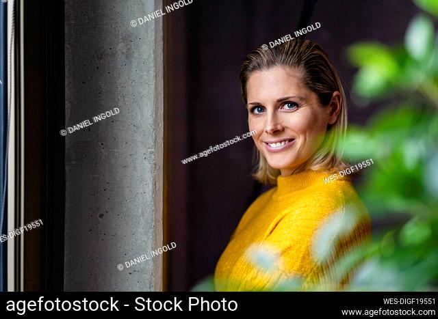 Happy businesswoman wearing yellow sweater in office