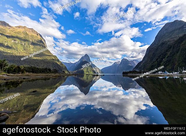 New Zealand, Scenic view of clouds and mountains reflecting on shiny surface of Milford Sound