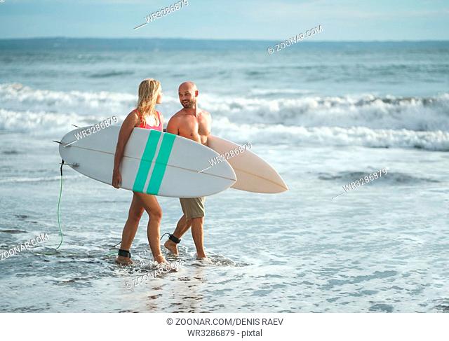 Young people with surfboards on the beach