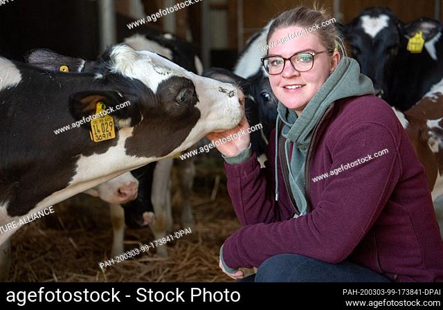 28 February 2020, Lower Saxony, Barsinghausen: Farmer Henriette Struß stroking a calf in the cowshed of her farm in Egestorf