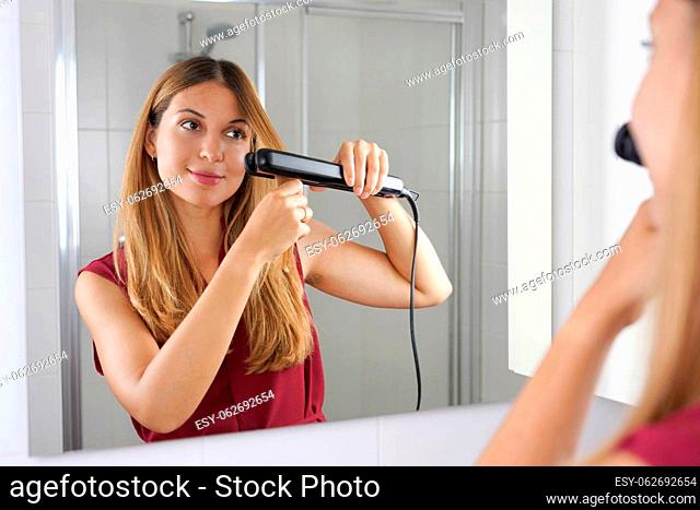 Beautiful young woman using streapod for straightening hair in an easy way at home