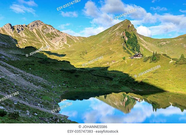 Mountain Rote Spitze and alpine hut Landsberger Hutte with reflection in lake