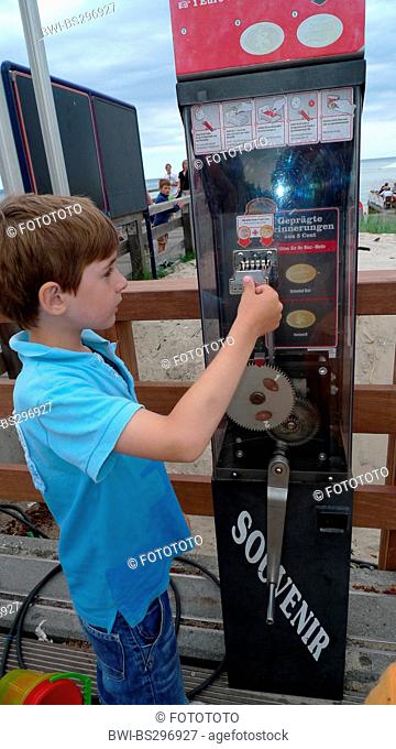 little boy at coin elongating machine, Germany, Mecklenburg-Western Pomerania, Ruegen