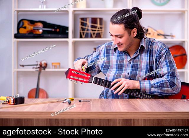 The young handsome repairman repairing guitar