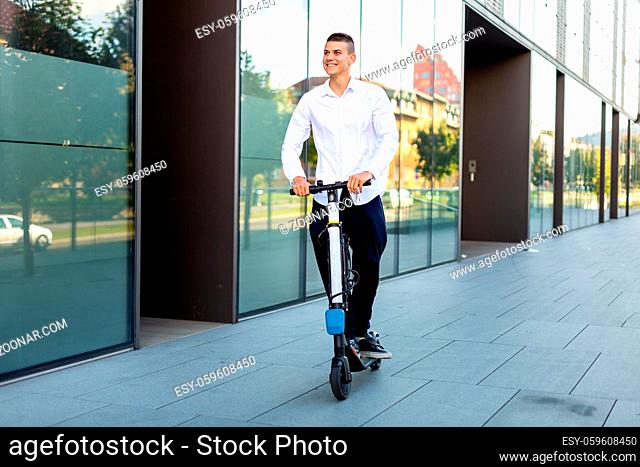 Young and casual business man riding electric scooter in the city