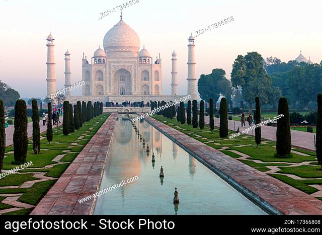 Taj Mahal and its water channel reflection. A classic, winter morning view of the mausoleum lit by the soft, pastel rays of the sun rising from the right-hand...