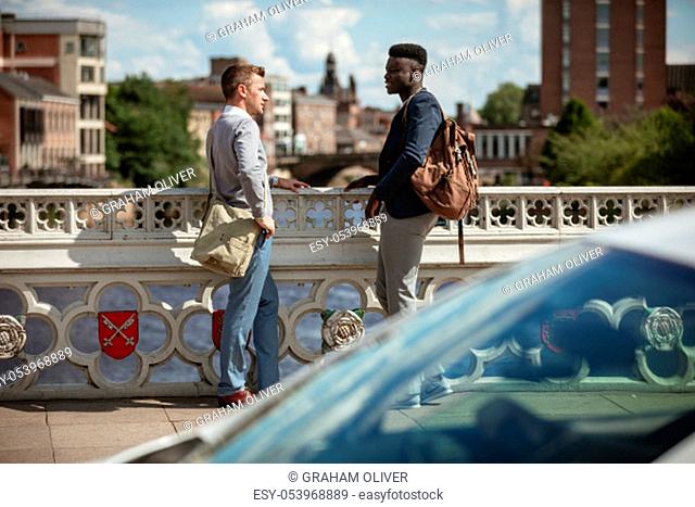 Two businessmen having a chat on a bridge in York. They are facing each other
