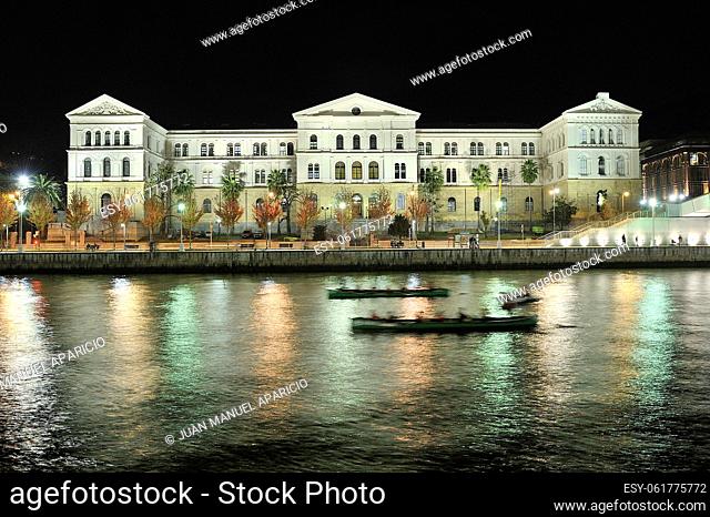 University of Deusto photographed at night with two drifters training on the river in the foreground