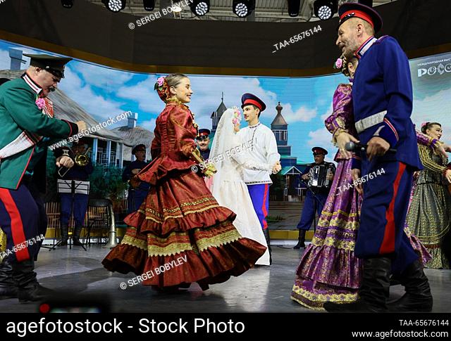 RUSSIA, MOSCOW - DECEMBER 12, 2023: Newlyweds Vladislav Kapustinsky and Alexandra Semenenko (R-L center) dance at a Don Cossack wedding during the Russia Expo...