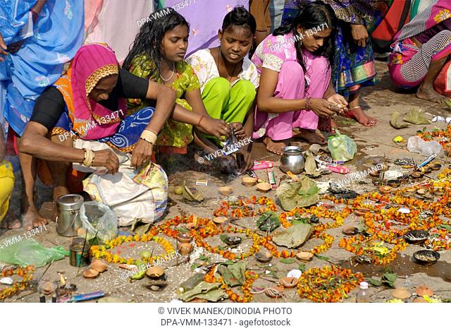 Girls performing pooja with incense sticks garlands with diyas at Dasaswamedh ghat ; Varanasi ; Uttar Pradesh ; India