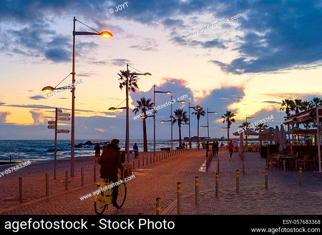 PAPHOS, CYPRUS - FEBRUARY 15, 2019: People walking by embankment at beautiful twilight in Paphos