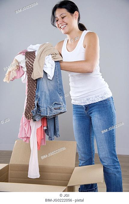 Young woman piling clothes into a cardboard box