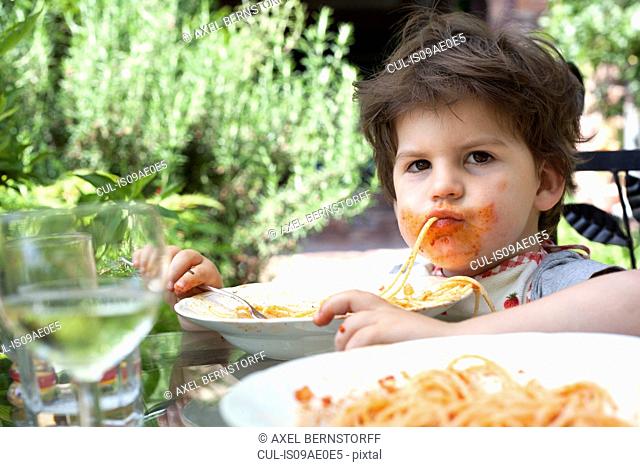 Portrait of messy male toddler eating spaghetti