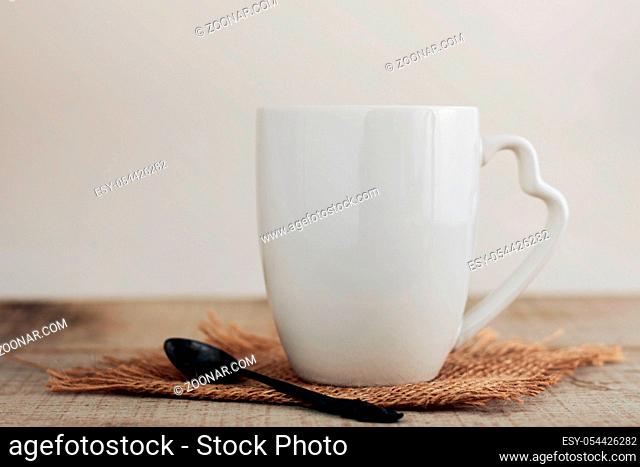 White cup and spoon on wooden with white background