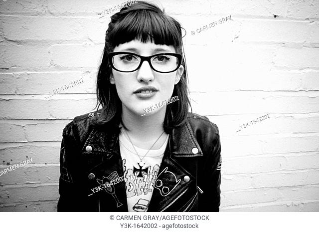 Black and white portrait of a young girl with glasses and a leather jacket