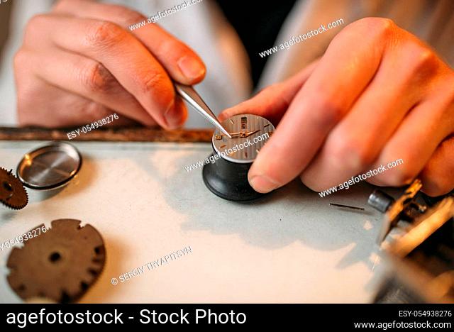 Watchmaker repair broken clockwork mechanism with small tweezers, macro view