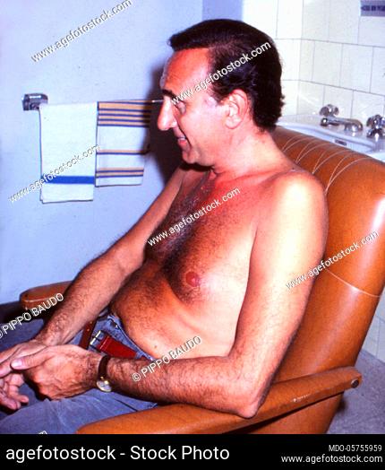 Italian television host Pippo Baudo shirtless in the dressing room. 1980s