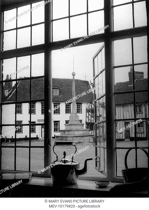 A view through the window of one of the perfectly preserved Tudor houses on Market Place, Lavenham looking out to the village cross