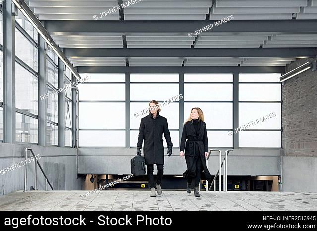 Woman and man with suitcase leaving train station