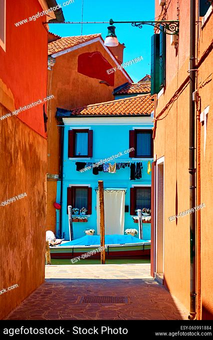 Small street by canal in Burano island in Venice, Italy. Venetian cityscape