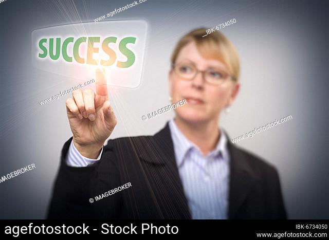 Attractive blonde woman pushing success button on an interactive touch screen, focus is on her finger