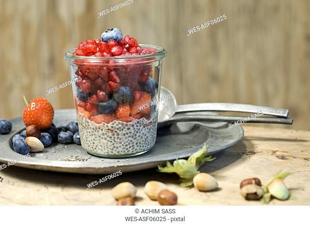 Glasses of chia pudding with different berries, pomegranate seeds and hazelnuts