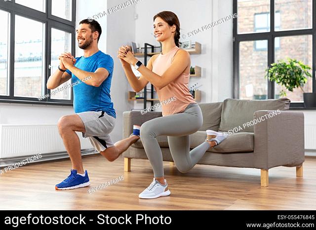 happy couple exercising and doing squats at home