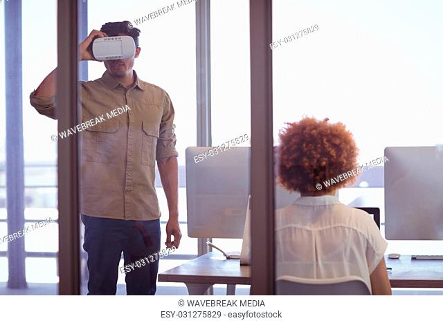 Businessman wearing VR headset with female colleague in office