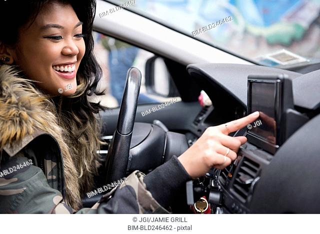 Mixed Race woman driving car pressing touch screen