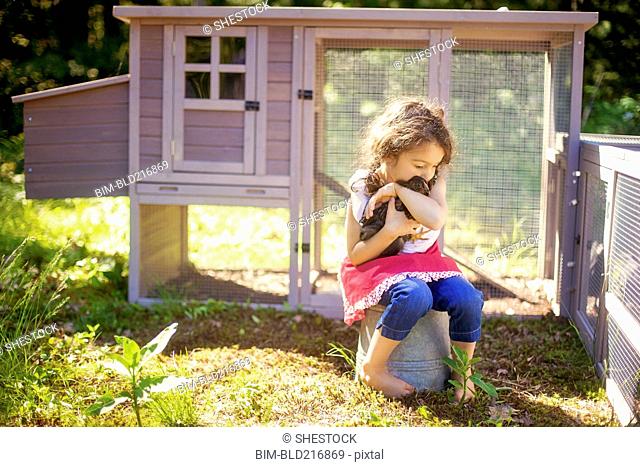 Girl hugging chicken in farm yard