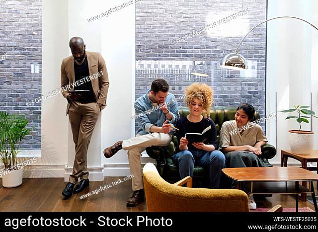 Business people sitting in modern coworking space brainstorming together