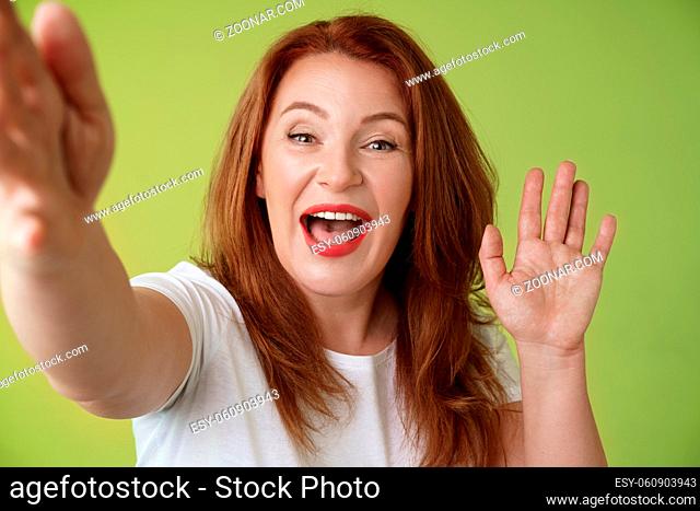 Friendly cheerful redhead middle-aged woman. extend arm hold camera taking selfie waving palm hi hello greeting smiling broadly welcome daughter talking...