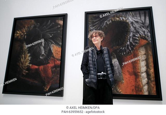 French photographer Sarah Moon stands with a camera around her neck in front of pictures at her exhibition in the Deichtorhallen arts center in Hamburg, Germany