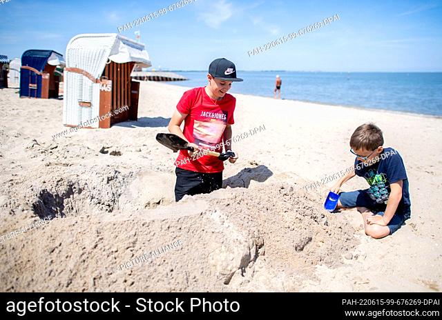 15 June 2022, Lower Saxony, Hooksiel: Simon and Jakob build a sandcastle on the North Sea beach in sunny weather. The North Sea Tourism Day 2022 will be held in...