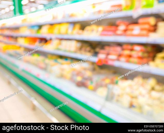 Defocused blur of supermarket shelves with sausages. Blur background with bokeh. Defocused image