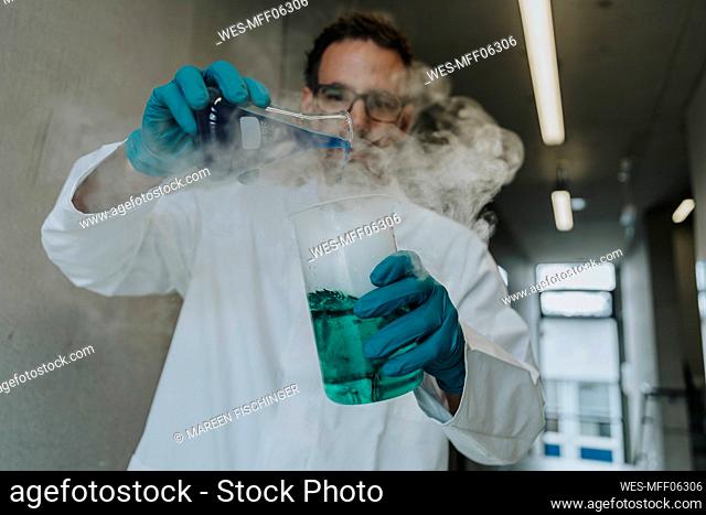 Scientist mixing liquid solution in flask while standing at clinic corridor