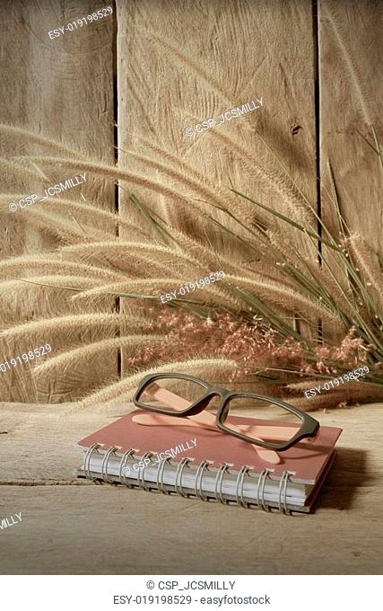 Still life notebook with foxtail grass on grunge wooden background, vintage style