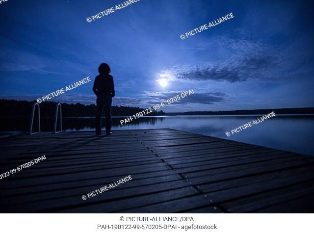 07 September 2017, Mecklenburg-Western Pomerania, Neukloster: A guest stands at full moon on a boat dock at the Seehotel am Neuklostersee
