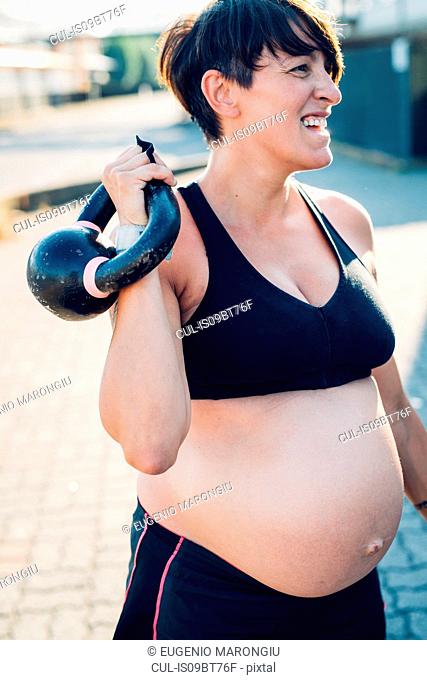 Pregnant woman using kettlebell outdoors