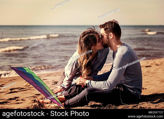 Young Couple having fun and Playing With A Kite On The Beach at autumn day filter