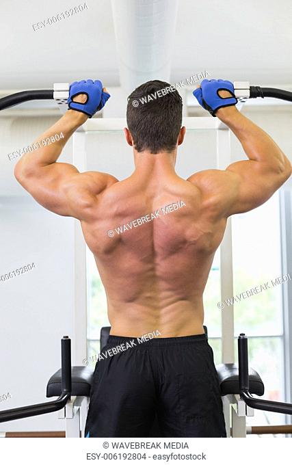 Male body builder doing pull ups at the gym