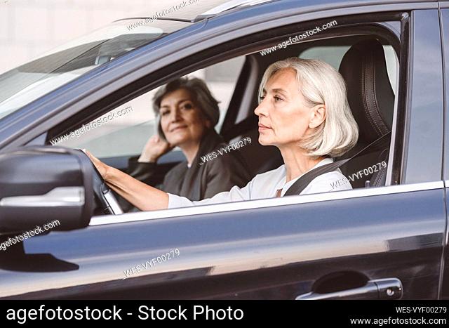 Colleague sitting with businesswoman while driving car in city